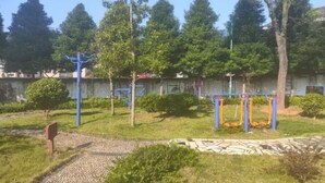 An outdoor area with exercise equipment, trees, and a paved path. - Jiayuan Holiday Hotel (Liuyang)