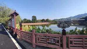 A wooden fence with a sign indicating a safety warning and a pond with lotus plants. - Jiayuan Holiday Hotel (Liuyang)