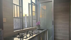 A modern kitchen with a gas stove, a sink, and a window. - Jiayuan Holiday Hotel (Liuyang)