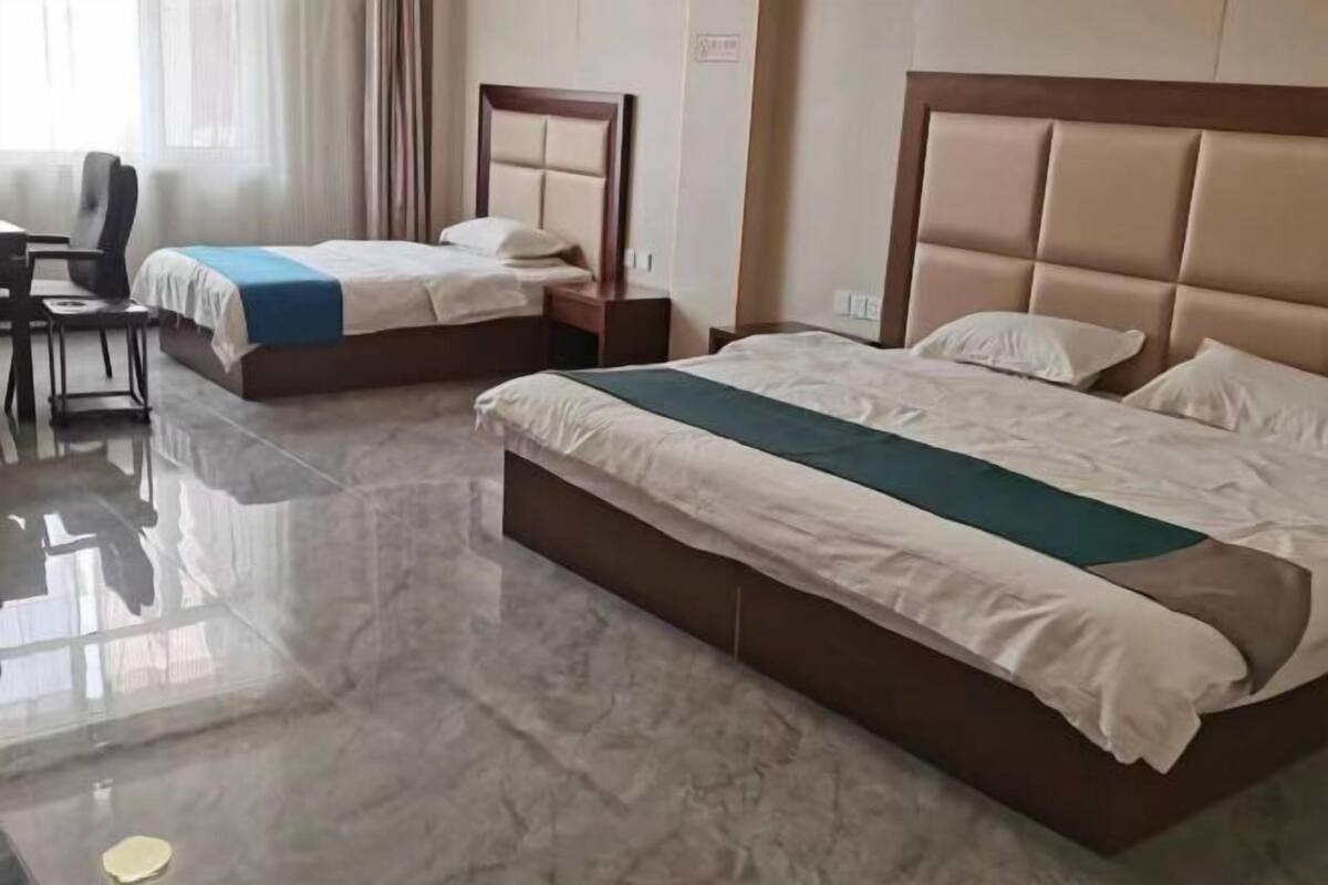 Habitación de hotel con dos camas, un escritorio y una silla.