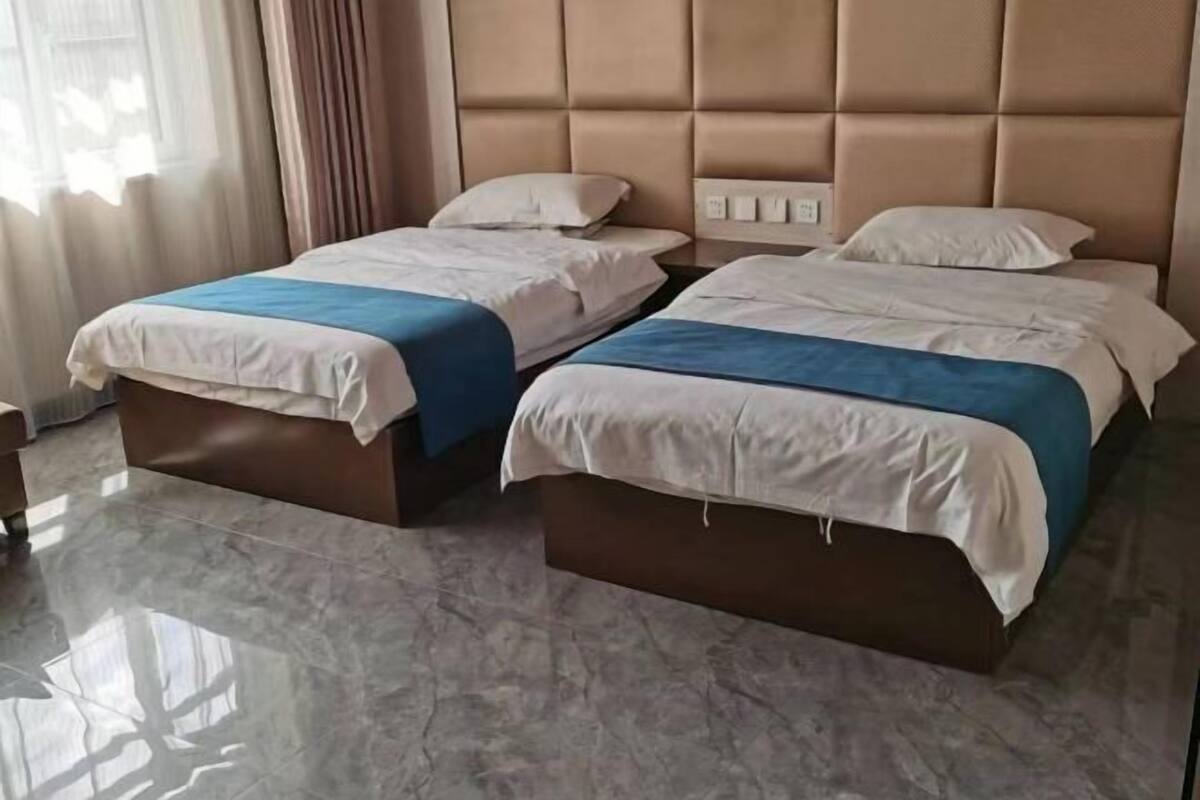 Una habitación de hotel con dos camas, suelo de mármol y cabecero acolchado.
