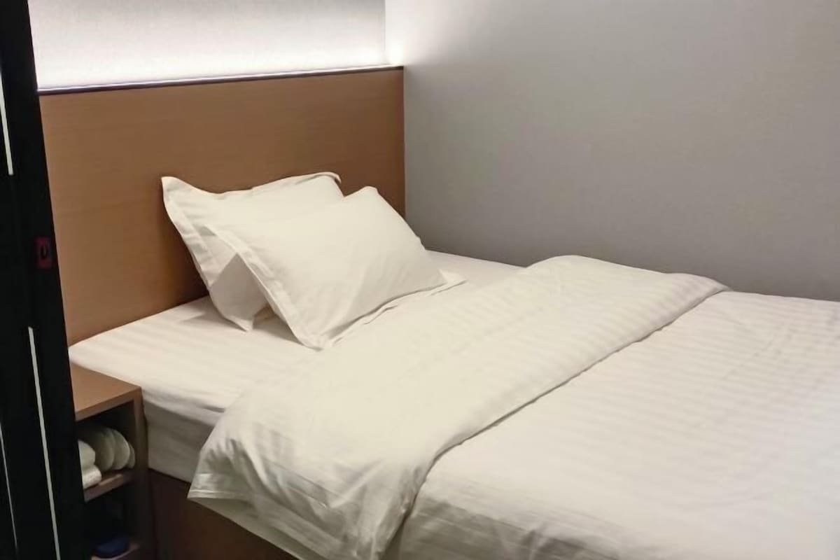 Un lit bien fait, avec du linge de lit blanc, dans une chambre d’hôtel.