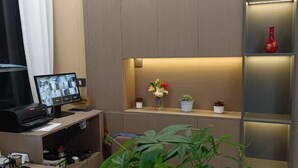 A reception desk with a computer monitor, printer, and keyboard. There are potted plants on the desk and shelves. - an County Zhengxing Business Hotel (Mianyang)