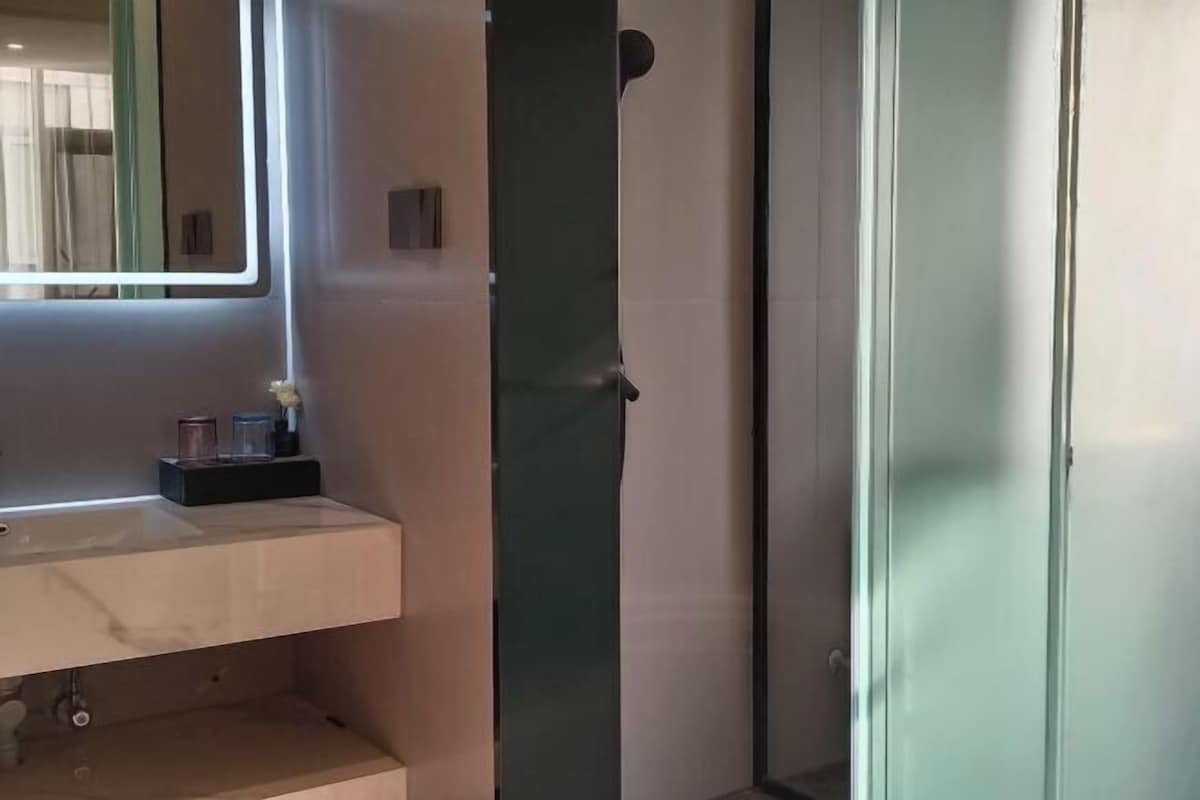 Une salle de bain avec un miroir, un lavabo et un espace douche.