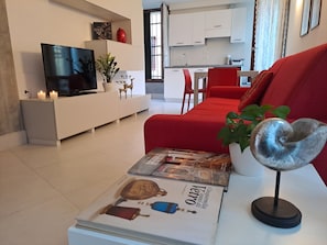 A modern living room with a red sofa, a TV, and magazines on a coffee table. - Romantic apartment with a view of the canal (Venezia)