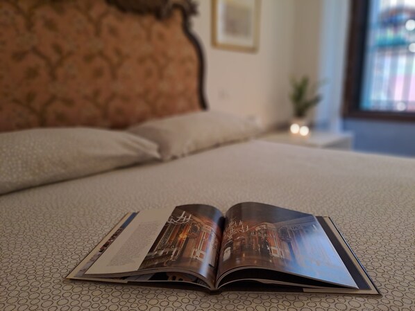 An open magazine on a bed with a patterned bedspread. - Romantic apartment with a view of the canal (Venezia)