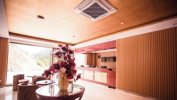 A modern hotel lobby with a round table, comfortable seating, a large window, and a view of the outdoors. - Shiniuzhai Pinru Villa (Pingjiang)