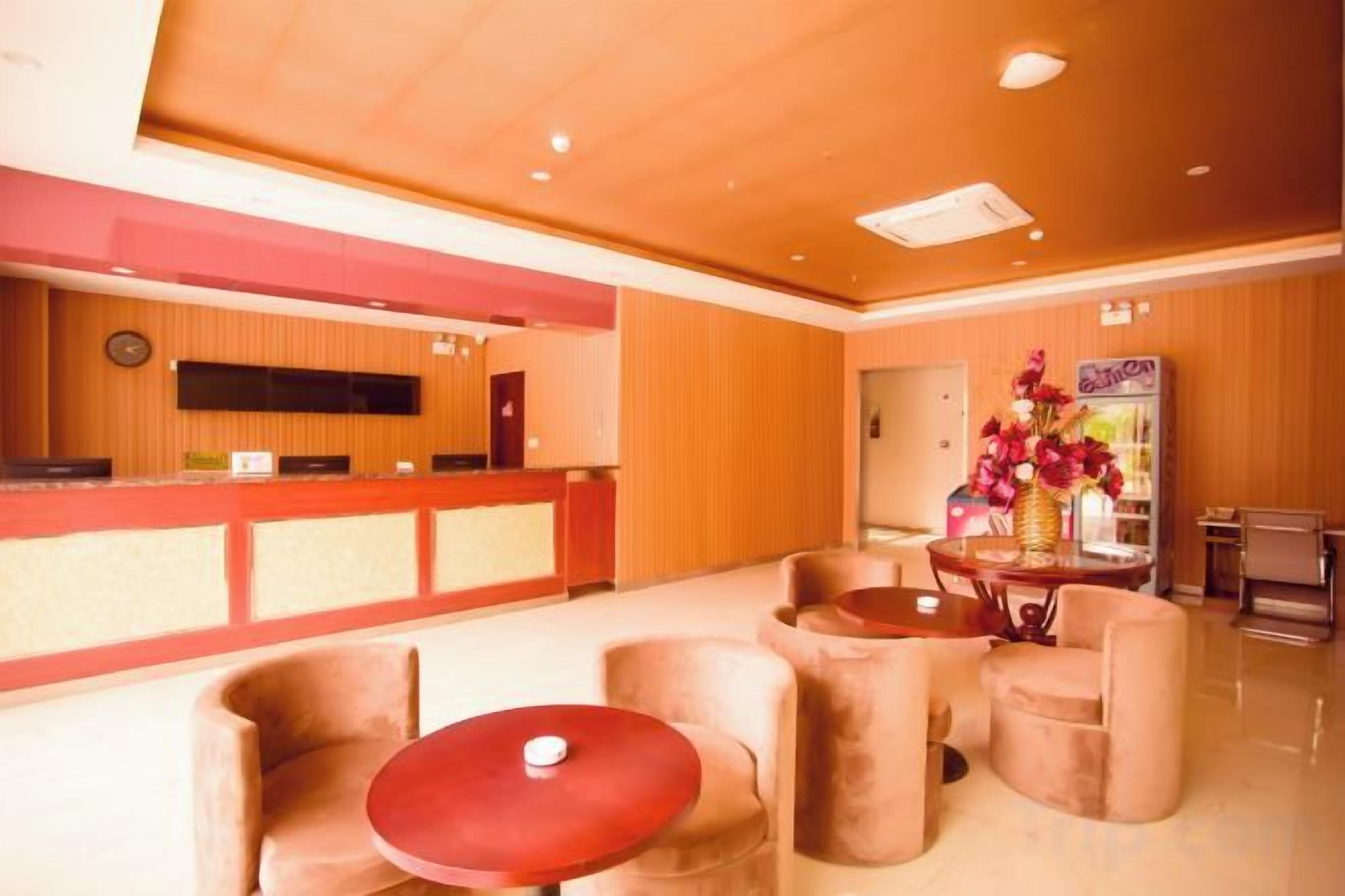 A hotel lobby with a reception desk, seating area, and a decorative vase.