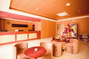 A hotel lobby with a reception desk, seating area, and a decorative vase. - Shiniuzhai Pinru Villa (Pingjiang)