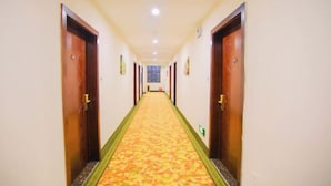 A hotel hallway with wooden doors, a patterned carpet, and a ceiling light. - Shiniuzhai Pinru Villa (Pingjiang)