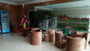 A lobby with a marble floor, a vending machine, a reception desk, a flower arrangement, and a glass wall with shelves of products. - Shiniuzhai Pinru Villa (Pingjiang)