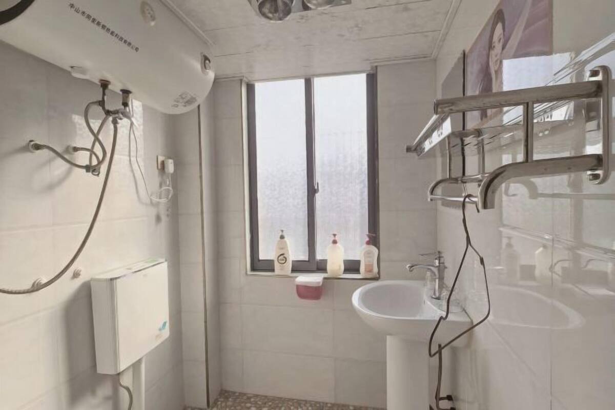 Baño con ducha, lavamanos y ventana.