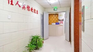 A hotel reception area with a reception desk, a wall-mounted sign, and potted plants.