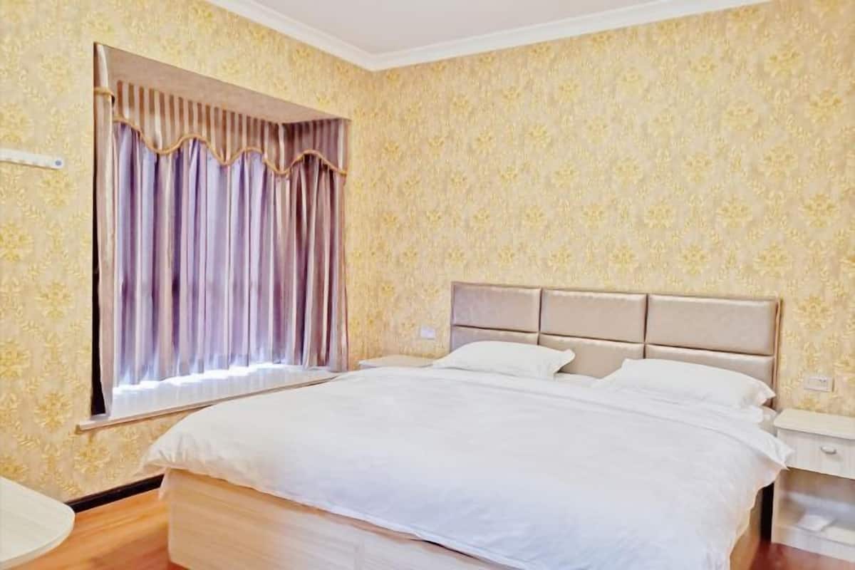 Habitación de hotel con cama, cortinas, mesita de noche y pared con estampado floral.