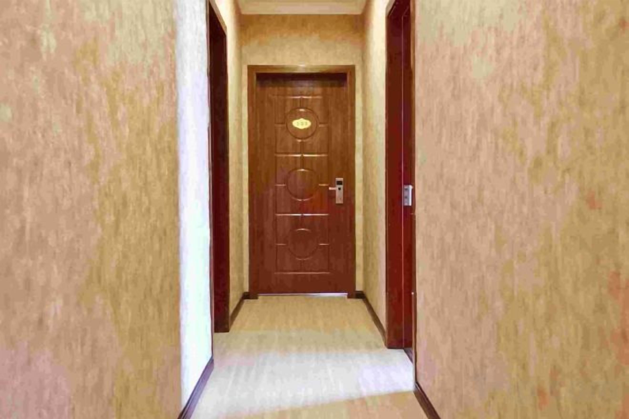 Un estrecho pasillo que conduce a una puerta de madera con pomo de latón y cerradura.