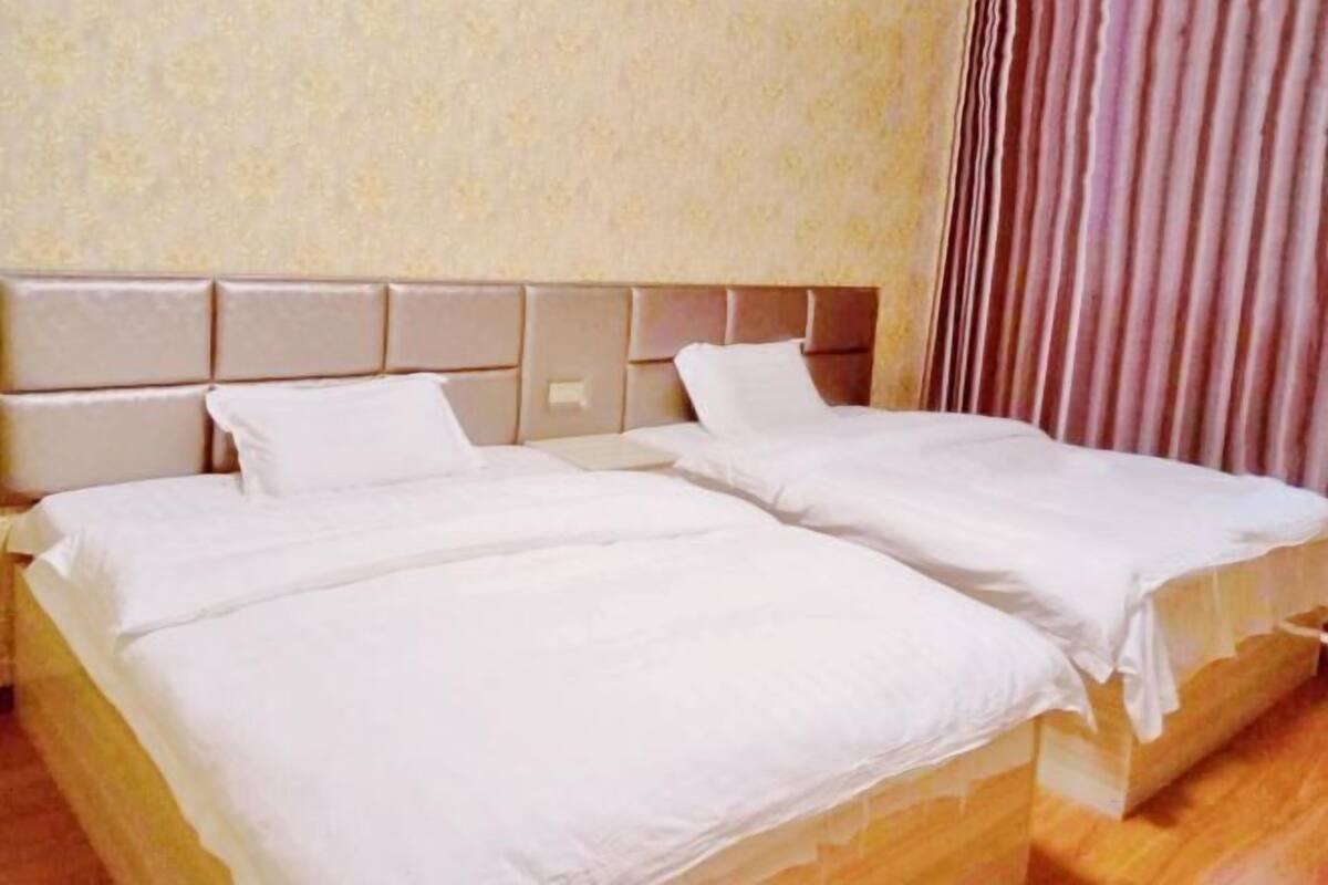 Una habitación de hotel con dos camas, un cabecero y una cortina.