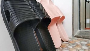 A pair of black and pink slippers on a tiled floor.