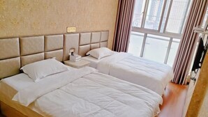 A hotel room with two beds, a headboard, a nightstand, and a window with curtains.