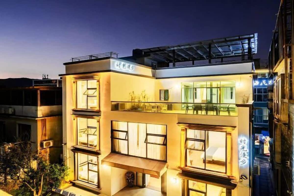A modern multi-story building with large windows and a balcony.