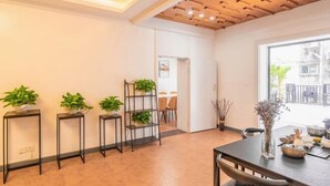 A modern dining area with a wooden ceiling, potted plants, and a table set for dining. - Time Walk Guesthouse (Shenzhen)