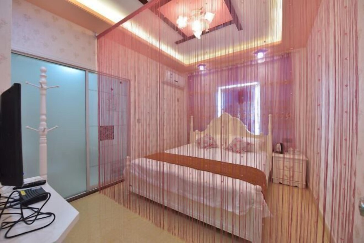 A bedroom with a bed, bedside table, and a window.