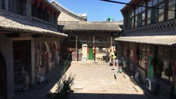 A traditional courtyard with tiled roofs, a central open space, and buildings on either side.