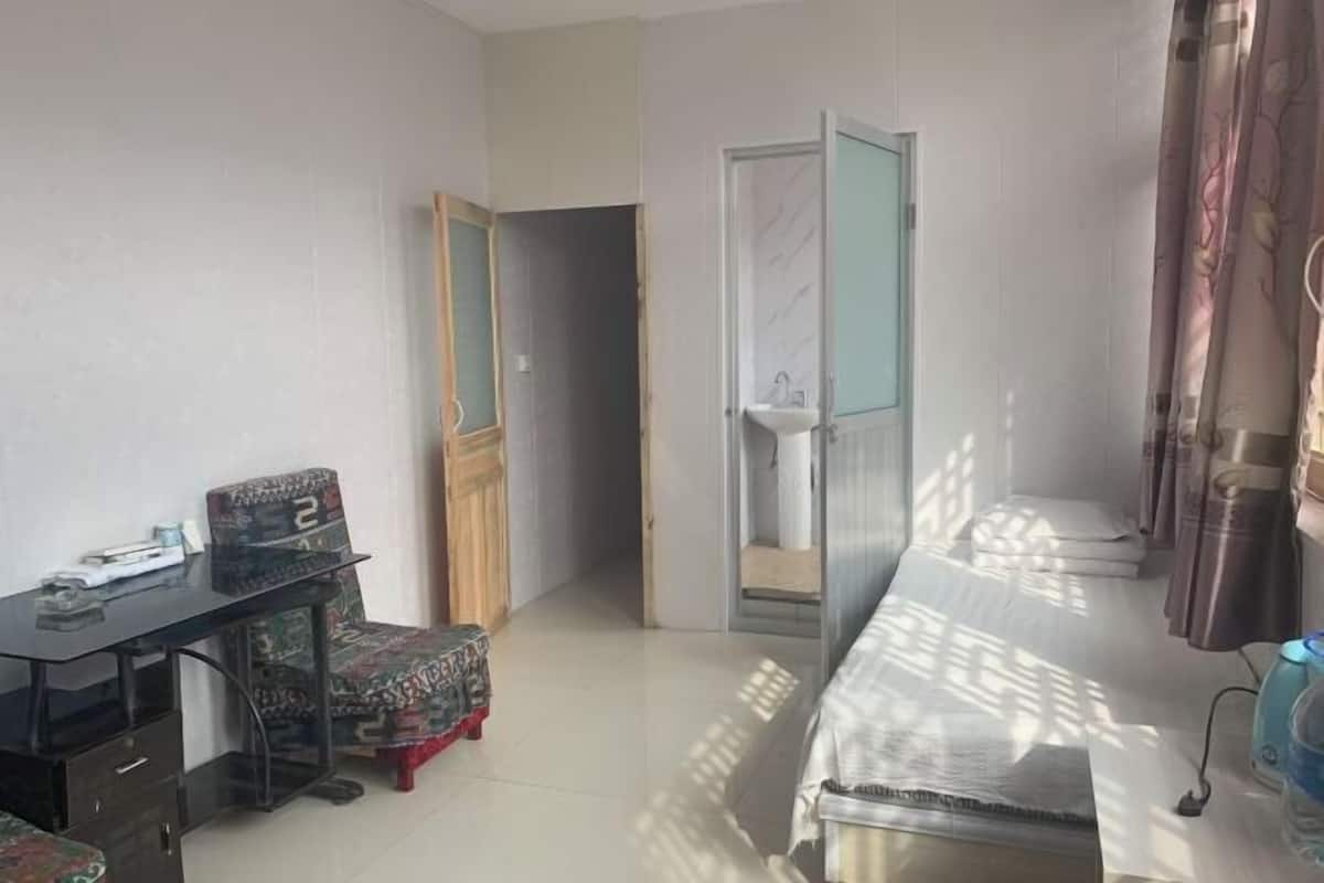 Ein Schlafzimmer mit Bett, Schreibtisch, Stuhl, Kleiderschrank und einer Badezimmertür.