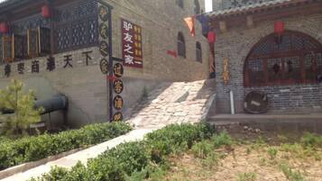 Um edifício tradicional com escadaria de pedra, um canhão e uma placa com caracteres chineses.