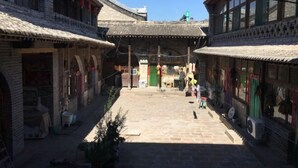 Ein traditioneller Innenhof mit Steinbauten, einem zentralen Platz und einer grünen Tür.