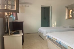 A bedroom with a bed, a desk, and a door leading to a bathroom.