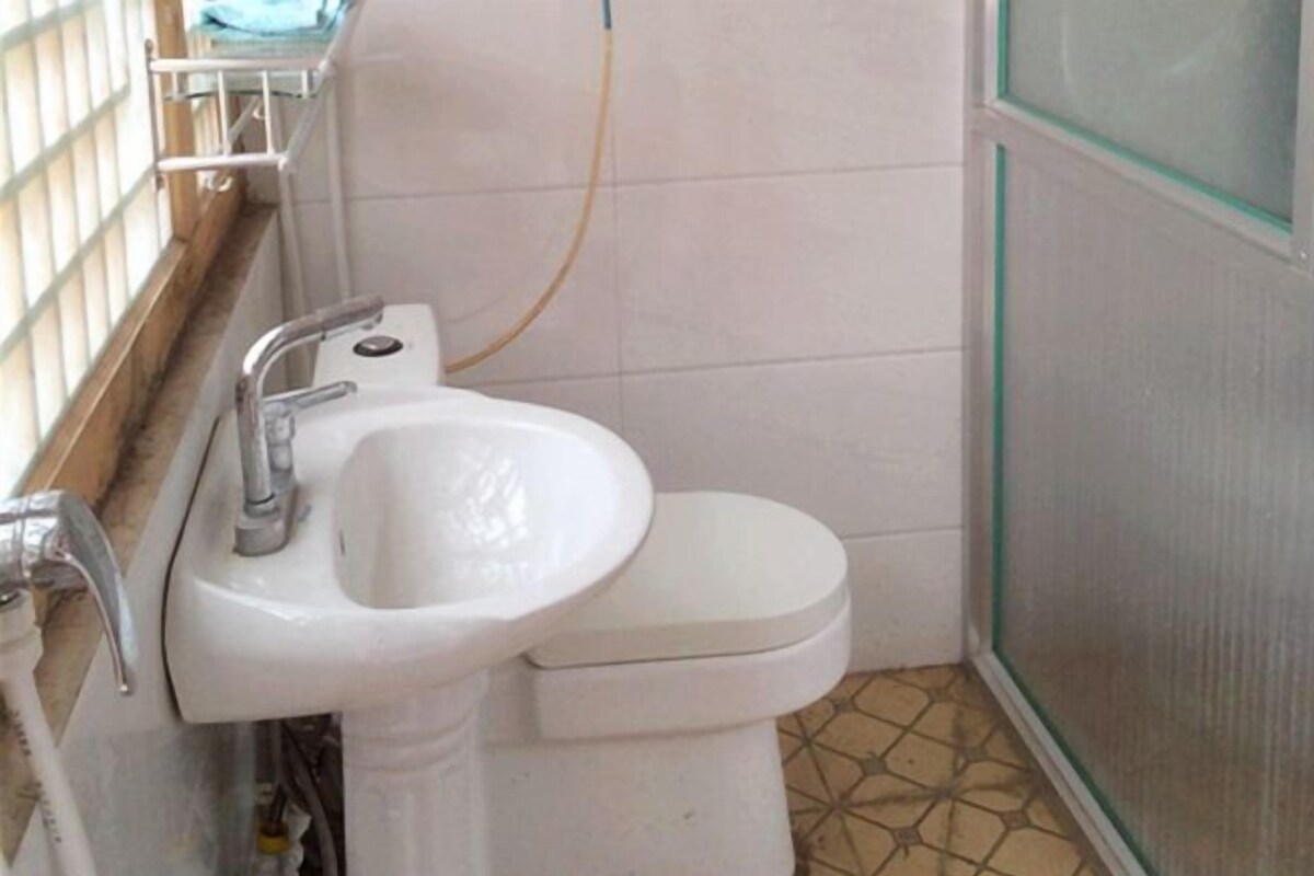 Een badkamer met een wit wastafel, toilet en raam met een metalen kader.