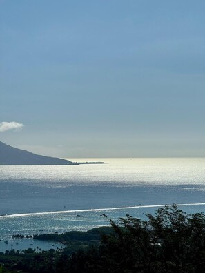 Un paysage côtier offrant une vue dégagée sur la mer, une montagne lointaine et une petite île.