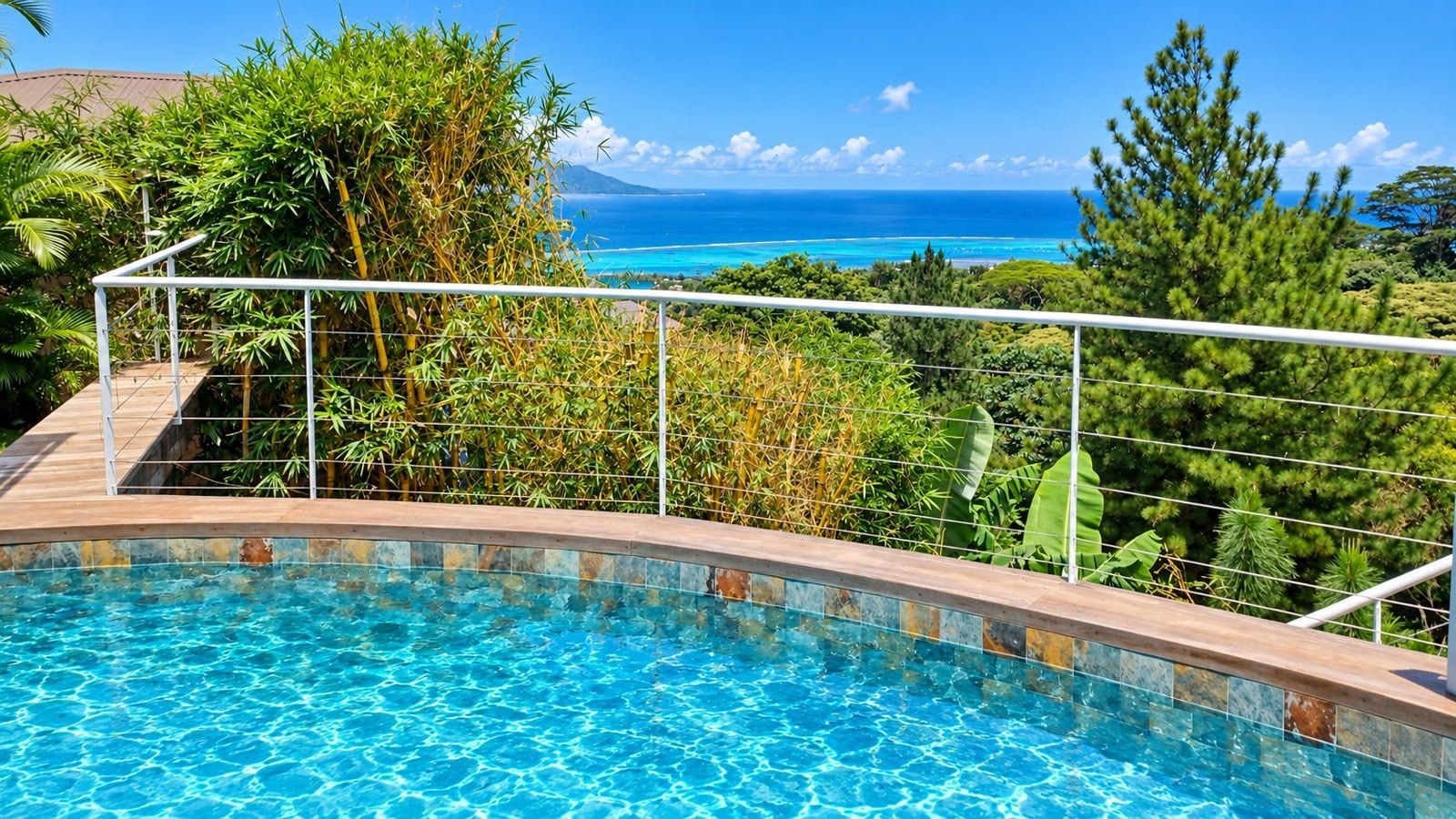 A swimming pool with a view of the ocean and tropical vegetation.