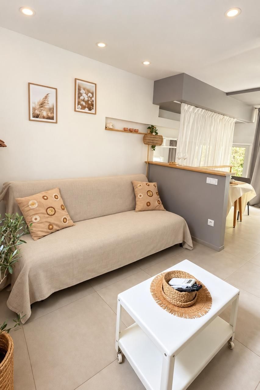 Ein modernes Wohnzimmer mit einer Couch, einem kleinen Tisch und einer Küchenzeile im Hintergrund.