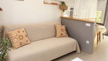 Ein modernes Wohnzimmer mit einer Couch, einem kleinen Tisch und einer Küchenzeile im Hintergrund.