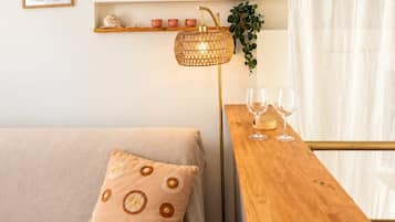 Ein zeitgemäßer Wohnraum mit einer Couch, einem Holztisch mit Gläsern, einer Stehlampe und einem Regal mit Dekoration.