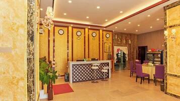 Un vestíbulo de hotel con mostrador de recepción, zona de estar y una pared decorativa con relojes.