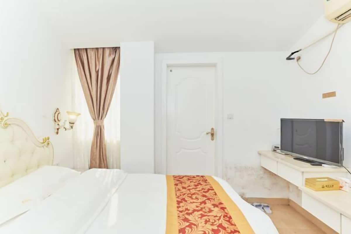 Een hotelkamer met een bed, een televisie, een bureau en een deur.