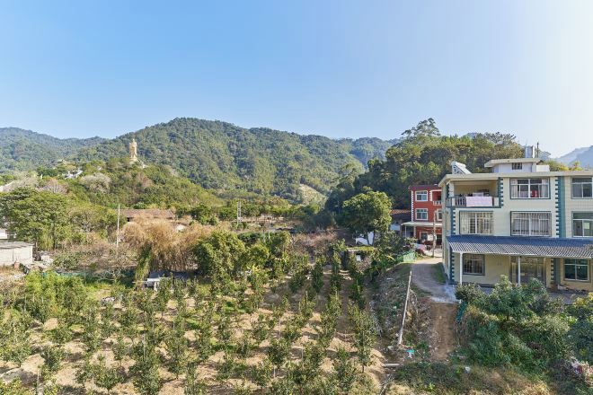 Una zona residencial con una colina, un edificio con balcones y un cielo despejado.