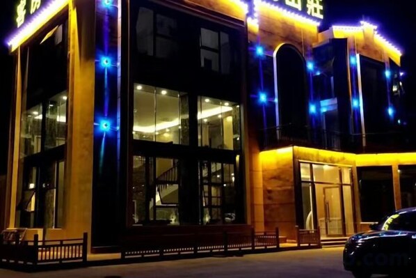 A building with large windows, a visible entrance, and a car parked in front.
