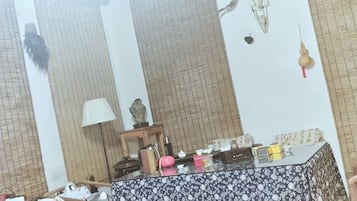 A room with a patterned tablecloth, a lamp, and various items on a table.