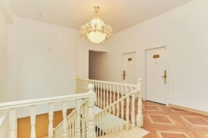 Una escalera con barandillas blancas y un candelabro, que conduce a una puerta con pomo de latón.