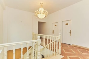 Una escalera con barandillas blancas y un candelabro, que conduce a una puerta con pomo de latón.