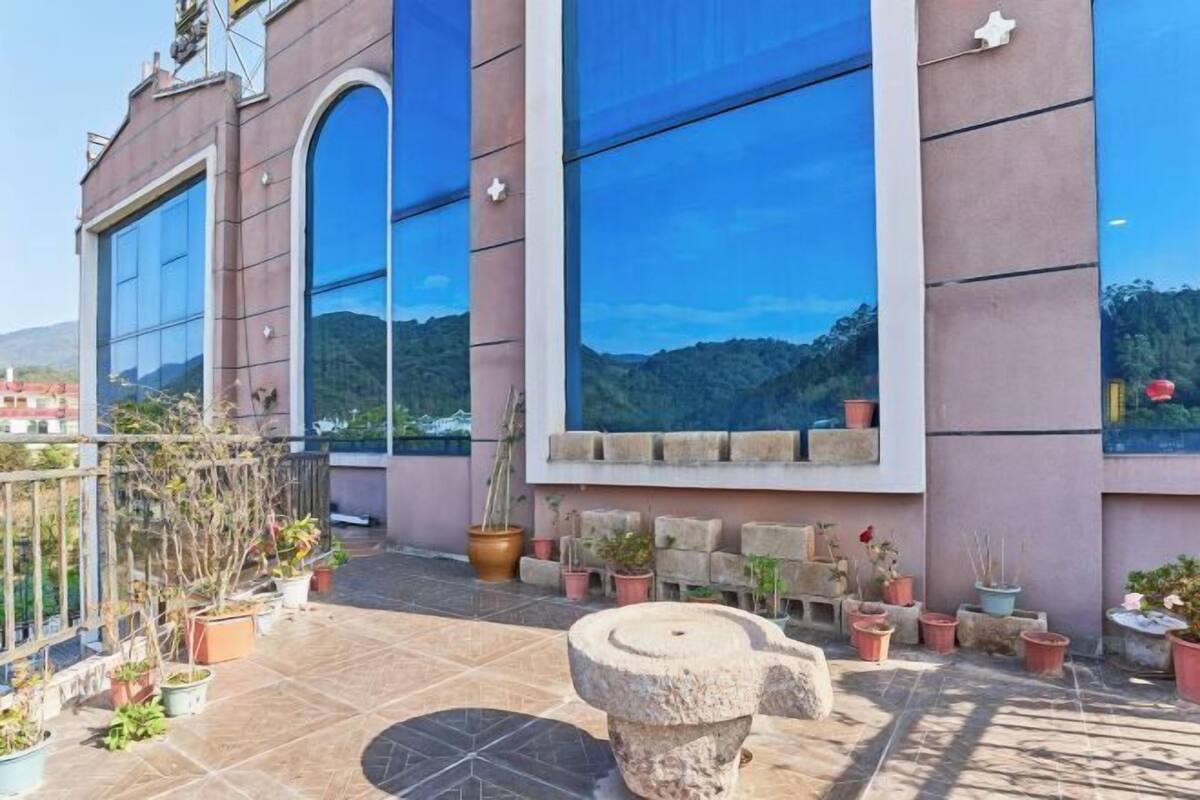 Een gebouw met grote ramen, een balkon met bloempotten en een stenen structuur.