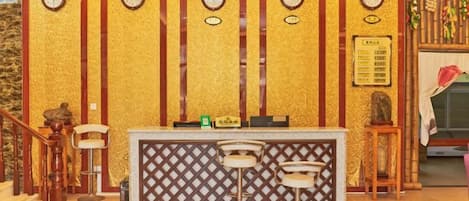 Una zona de recepción con mostrador, taburetes de bar y relojes en la pared.