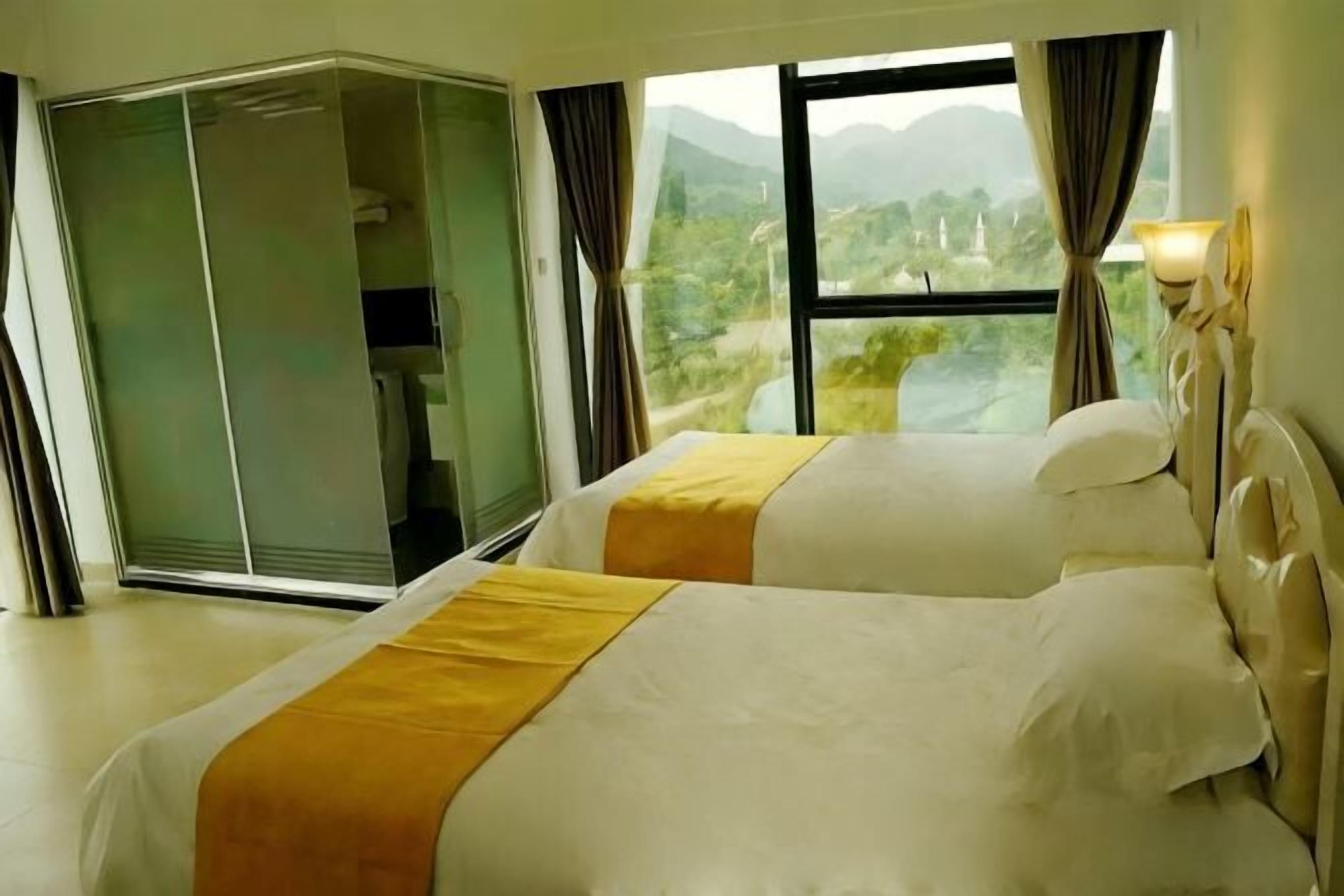 Une chambre d’hôtel avec deux lits, une porte-fenêtre coulissante et une vue sur un paysage montagneux.