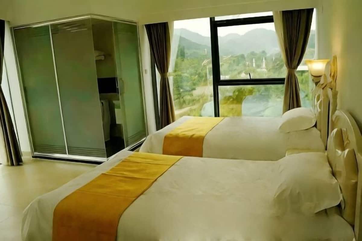 Hotelkamer met twee bedden, een schuifdeur en uitzicht op een bergachtig landschap.