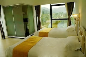 Une chambre d’hôtel avec deux lits, une porte-fenêtre coulissante et une vue sur un paysage montagneux.
