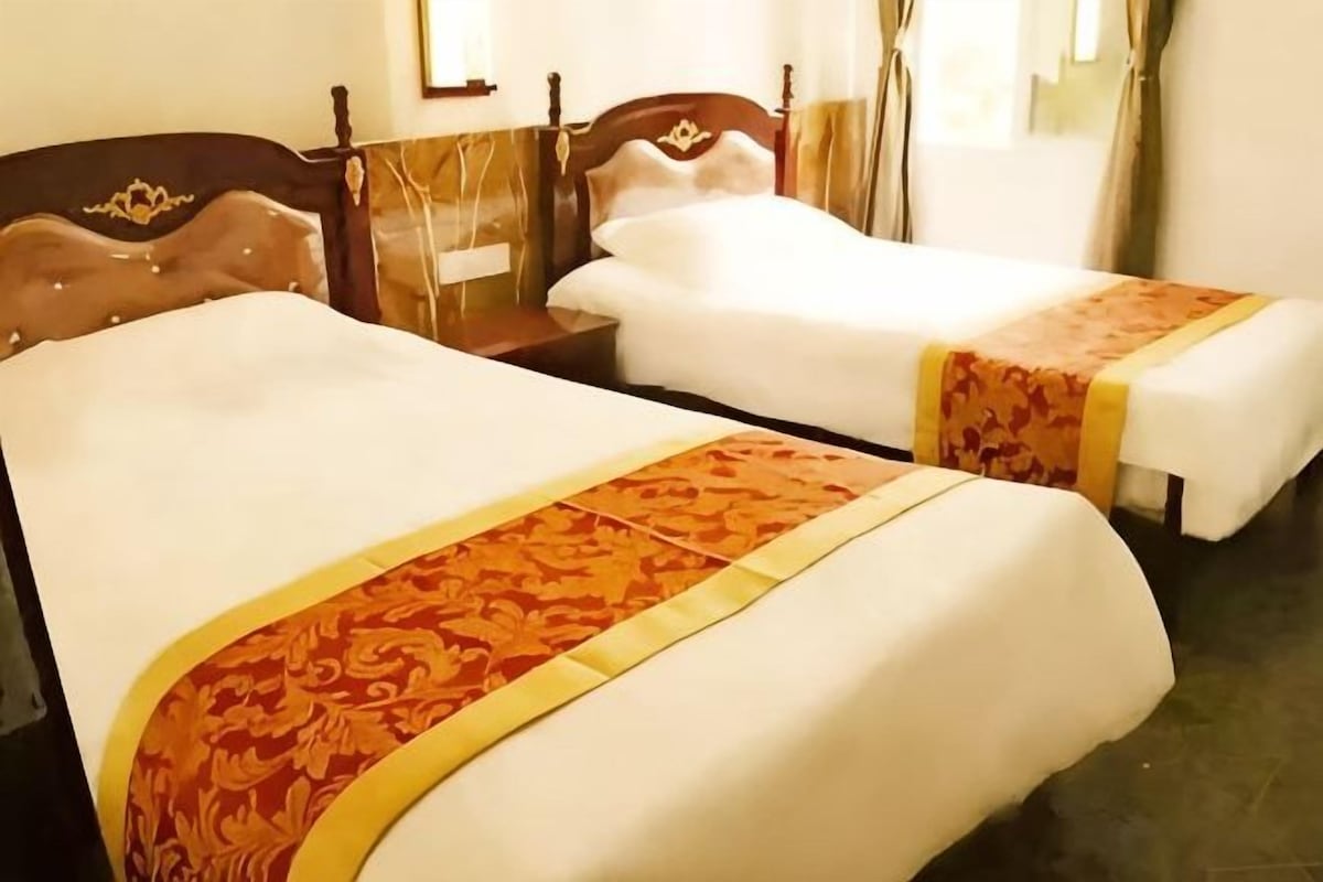 A hotel room with two beds, each with a patterned bedspread and a headboard.