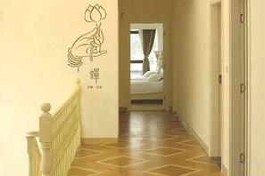A hallway with a wooden floor, a white railing, and a bed visible in the distance. - Xiangyue Villa Hotel (Pinghe)